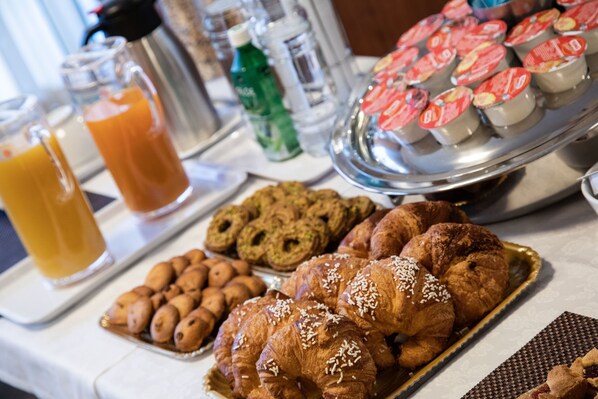 Una mesa de buffet con diversos alimentos, incluyendo pasteles, galletas y jugo.