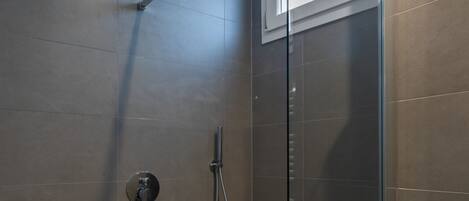 Una ducha moderna con puerta de cristal, cabezal de ducha manual y panel de control.