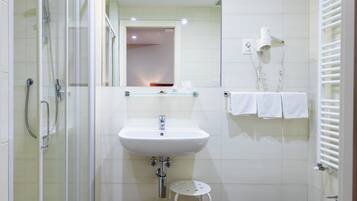 Un bagno moderno con box doccia in vetro, lavabo su piedistallo, bidet e specchio sopra il lavabo.
