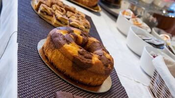 A buffet table with various baked goods, including pastries and a bundt cake, and a selection of beverages.
