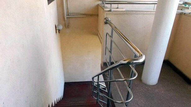 Una escalera con barandillas de metal y una cesta metálica en la parte inferior.