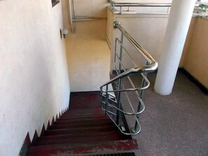 Una escalera con barandillas de metal y una cesta metálica en la parte inferior.