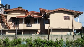 Un edificio de dos plantas con fachada color beige, techo de tejas rojas y un pequeño balcón.