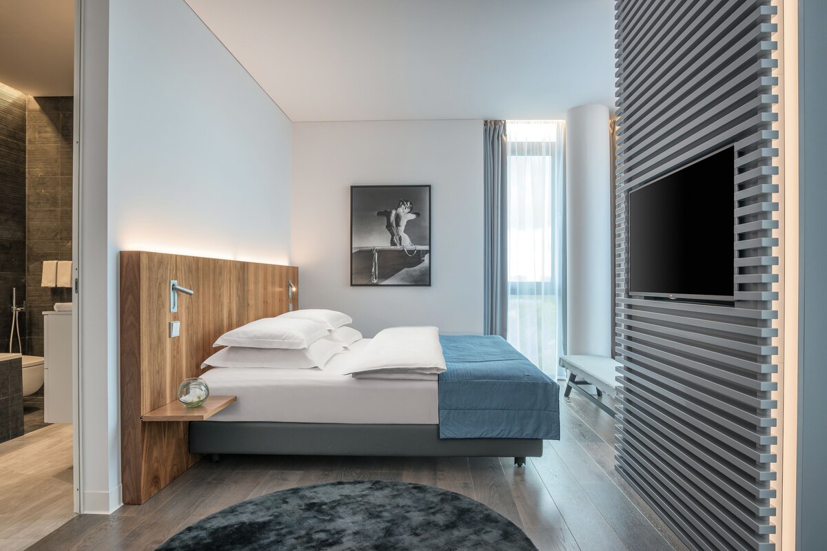 Une chambre à coucher moderne avec un lit, une table de chevet et un téléviseur fixé au mur.
