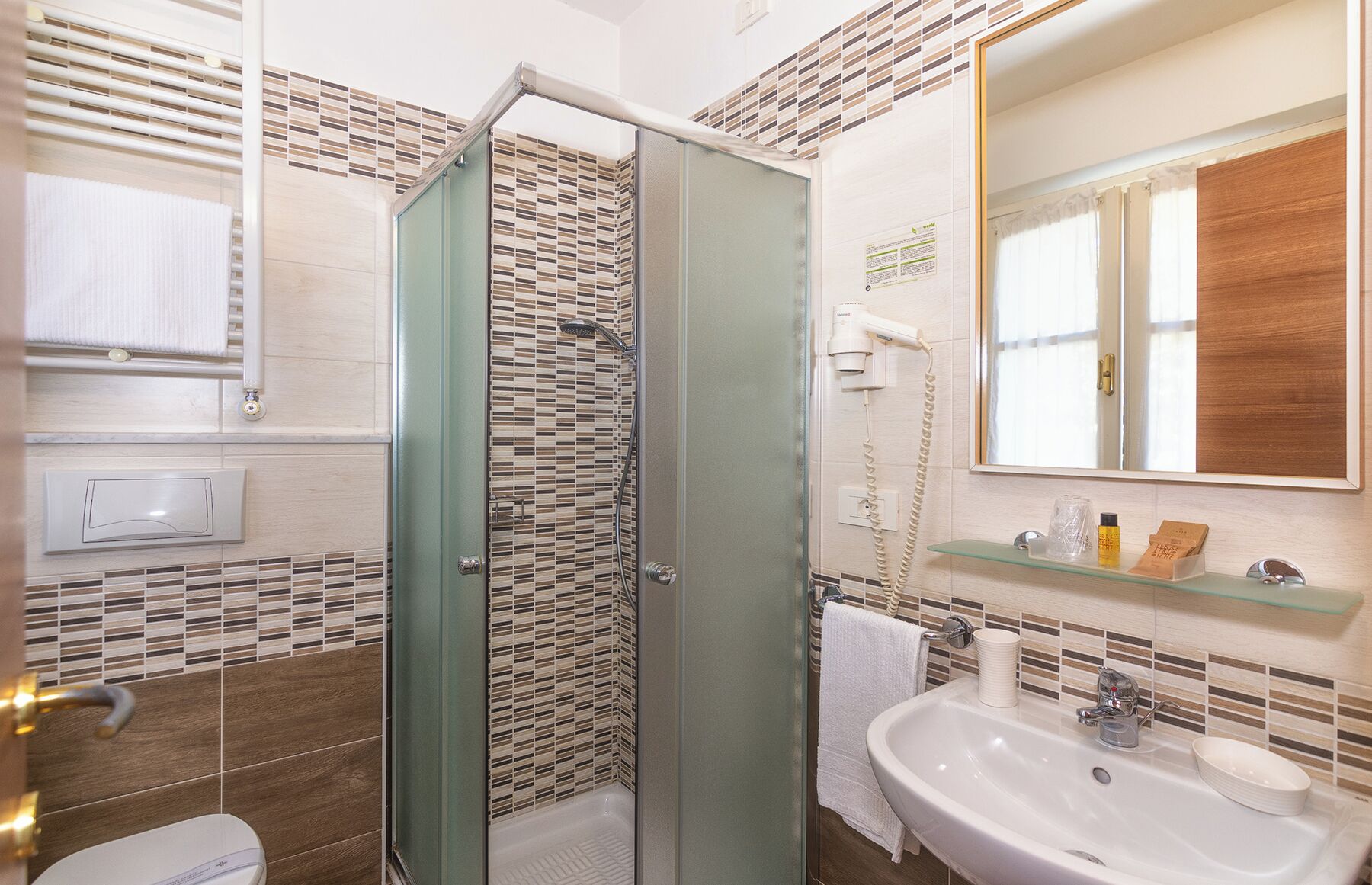 A bathroom with a glass shower enclosure, a sink, a mirror, and a towel rack.