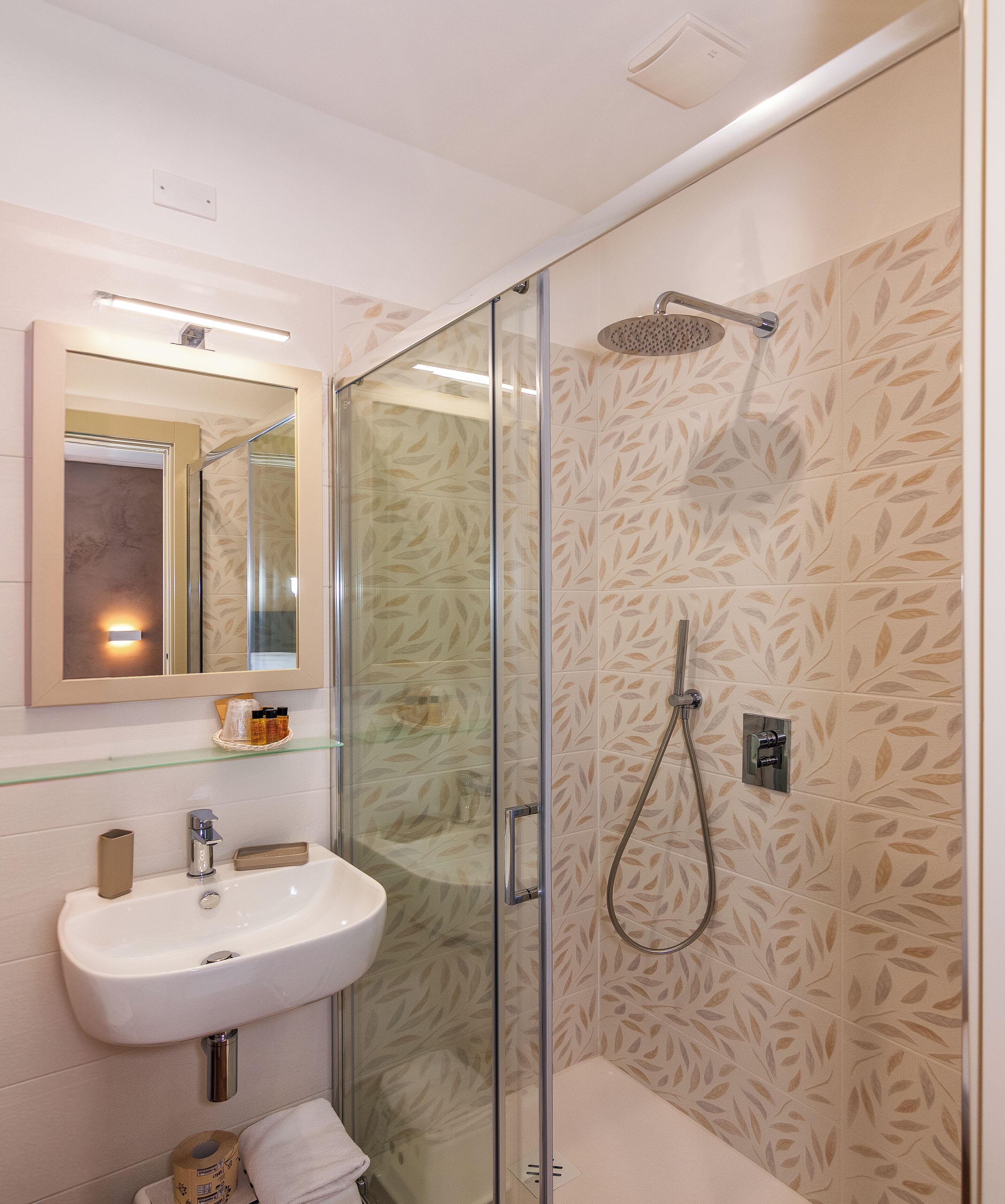 Un baño con ducha de vidrio, lavamanos blanco y espejo sobre él.