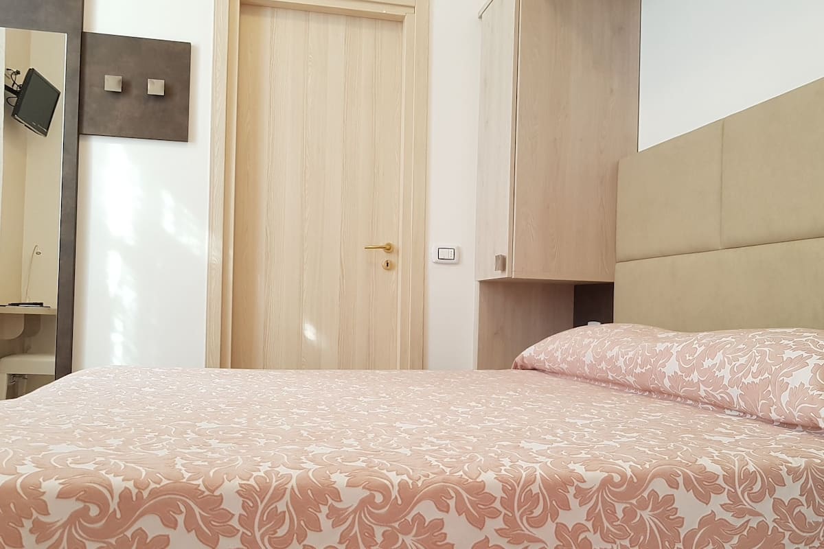 A bedroom with a bed, a wardrobe, and a mirror.