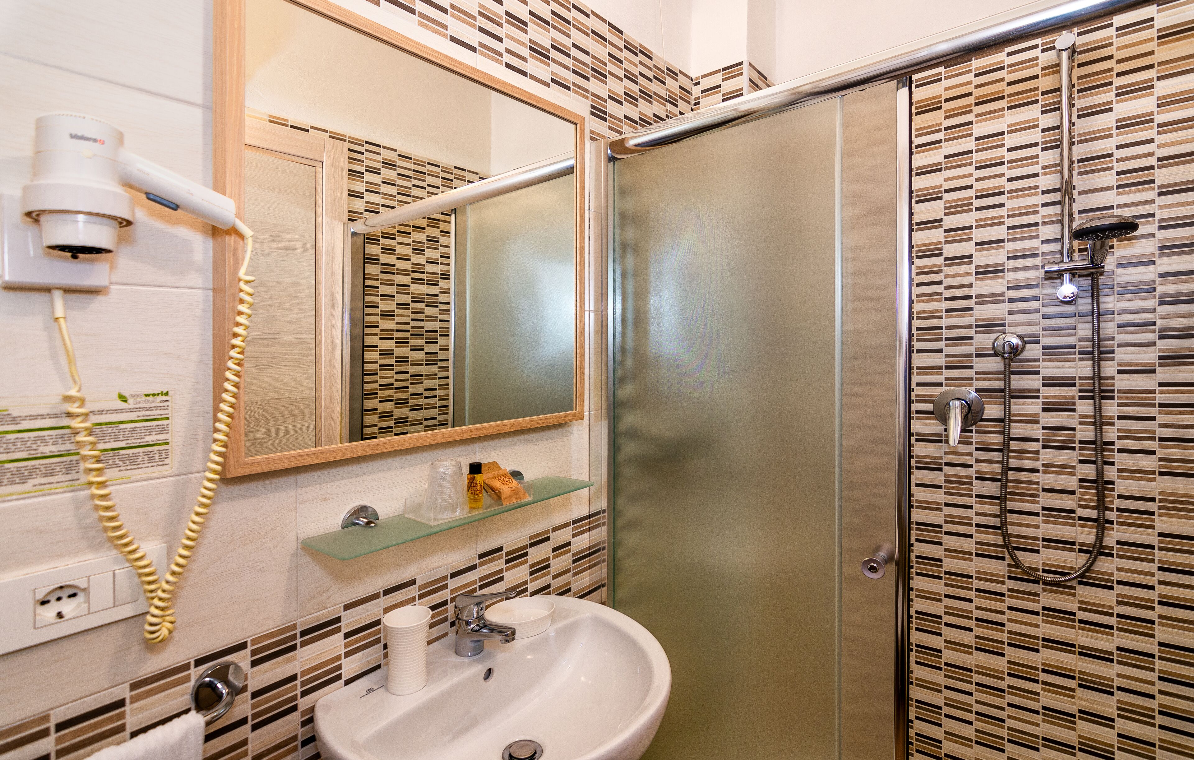 A bathroom with a sink, mirror, and a shower enclosure.