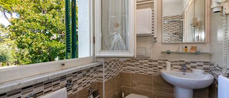 Une salle de bain avec des toilettes, un lavabo et une fenêtre.