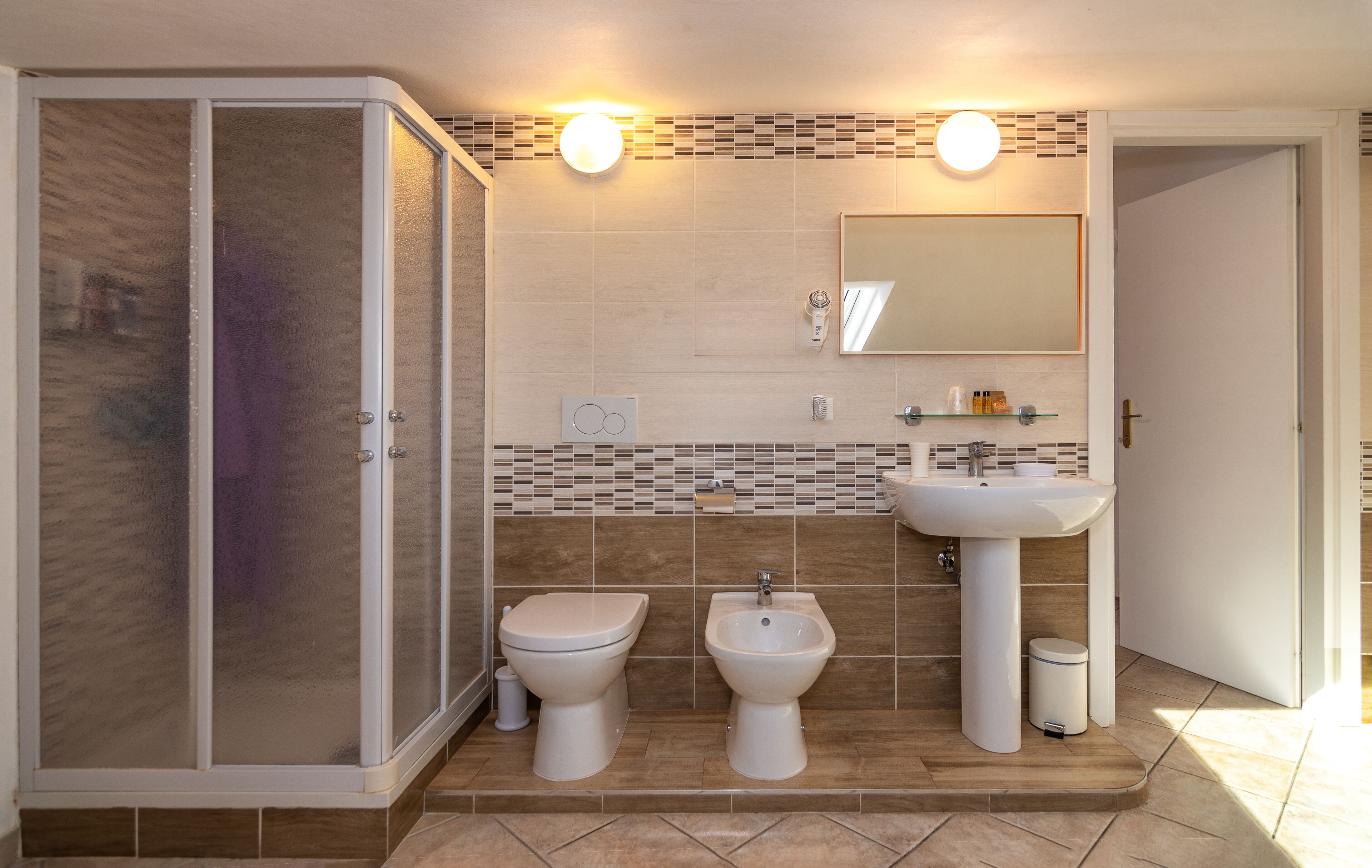 Un baño con cabina de ducha, inodoro, bidé y lavabo.