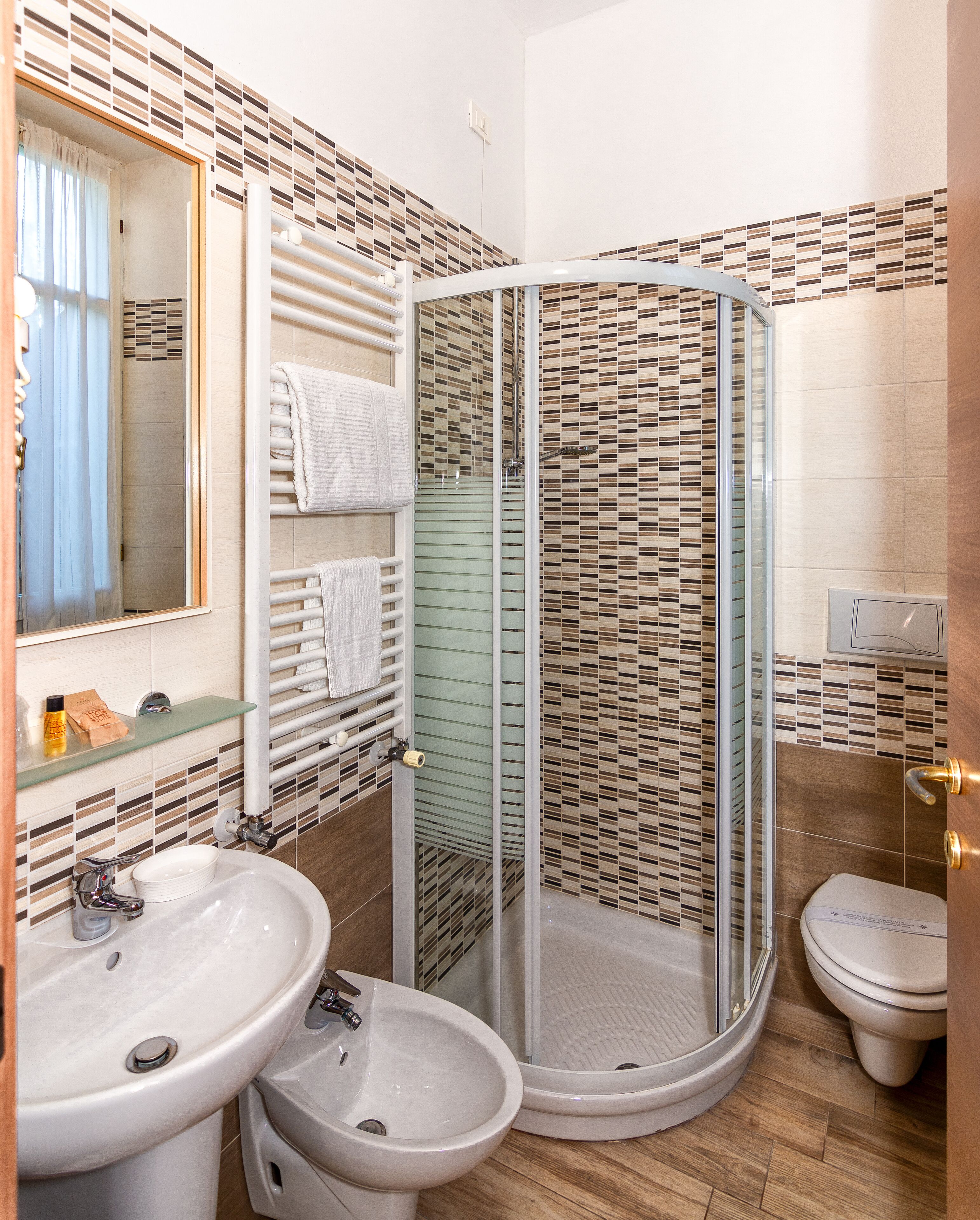 Een badkamer met een douche met glazen wand, een wastafel, een toiletbrons en een toilet.