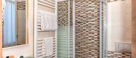 A bathroom with a glass-enclosed shower, a sink, a bidet, and a toilet.