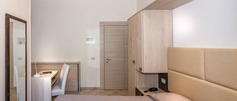 A bedroom with a bed, a desk, a chair, a wardrobe, and a door.