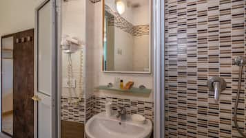 A bathroom with a white sink, a mirror, a hairdryer, and a shower.