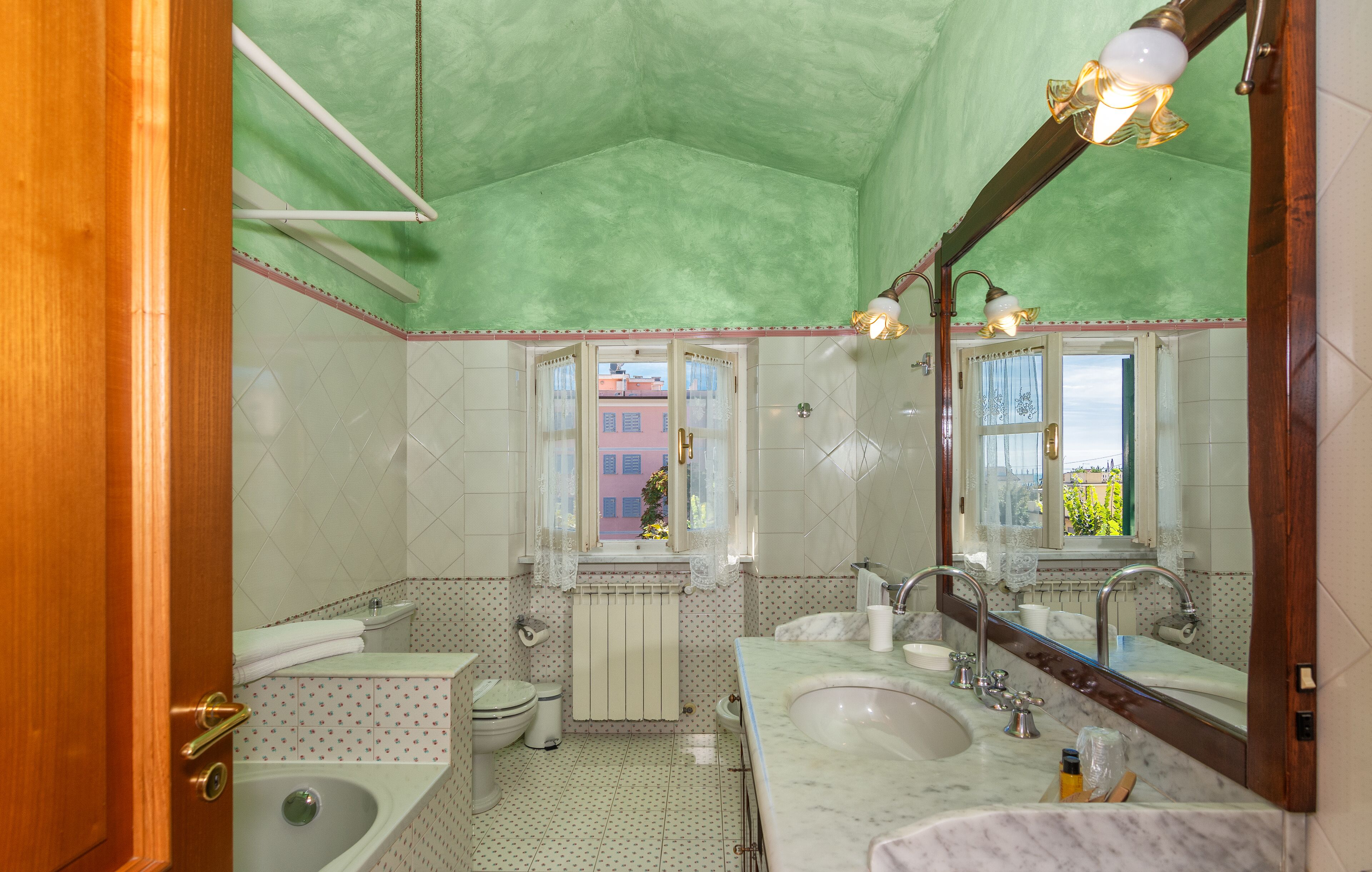 A bathroom with a green ceiling, two sinks, a bathtub, and a toilet.