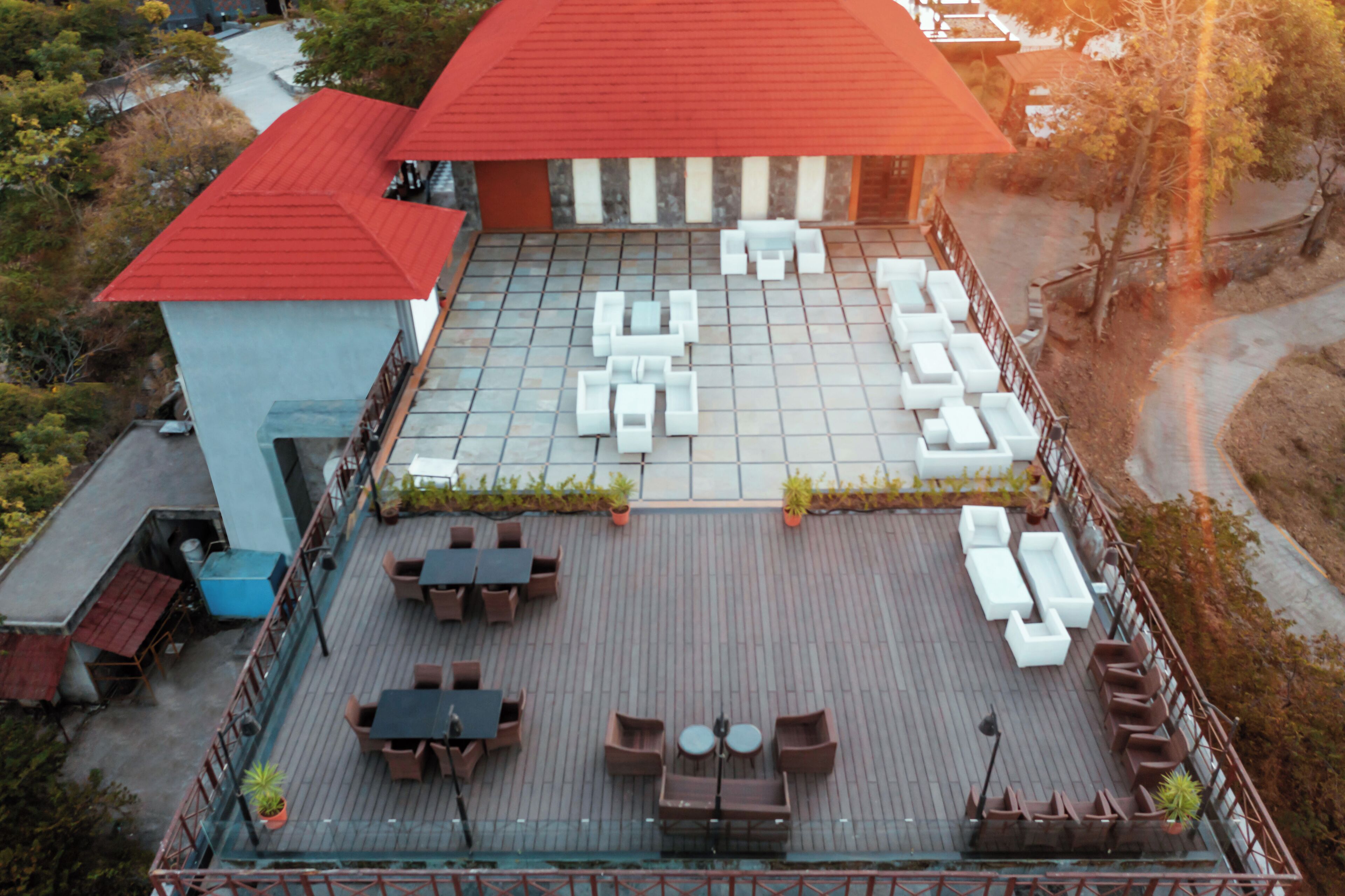 Una terraza en la azotea con mobiliario exterior y un edificio con tejado rojo.