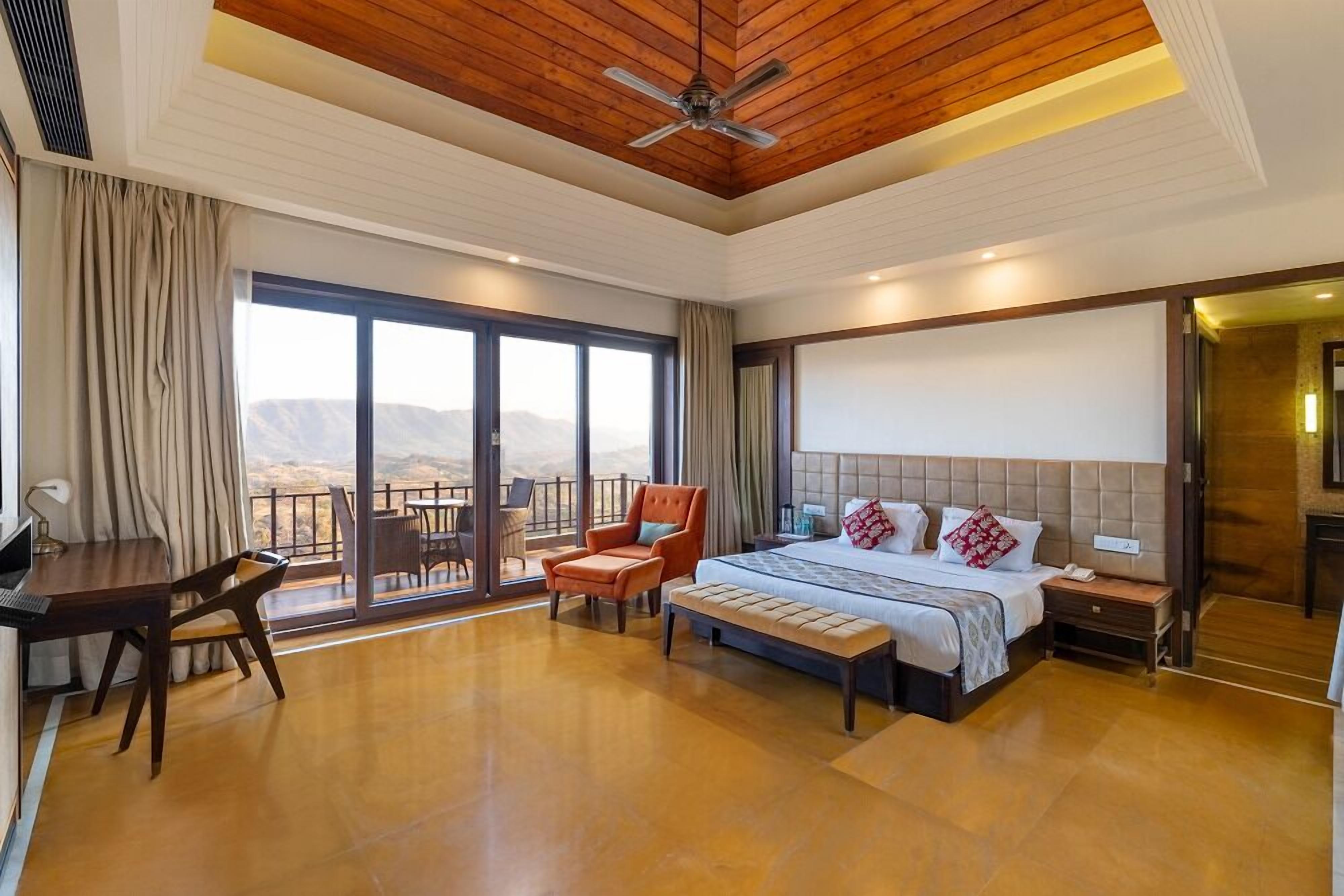Ein geräumiges Schlafzimmer mit einem großen Bett, einem Schreibtisch und einem Stuhl, inklusive Balkon mit Bergblick.