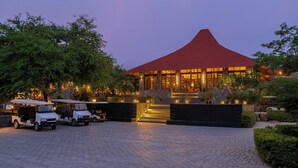 A building with a red roof, a paved entrance, and a parking area with golf carts. - Mahua Bagh Resort (Kumbhalgarh)