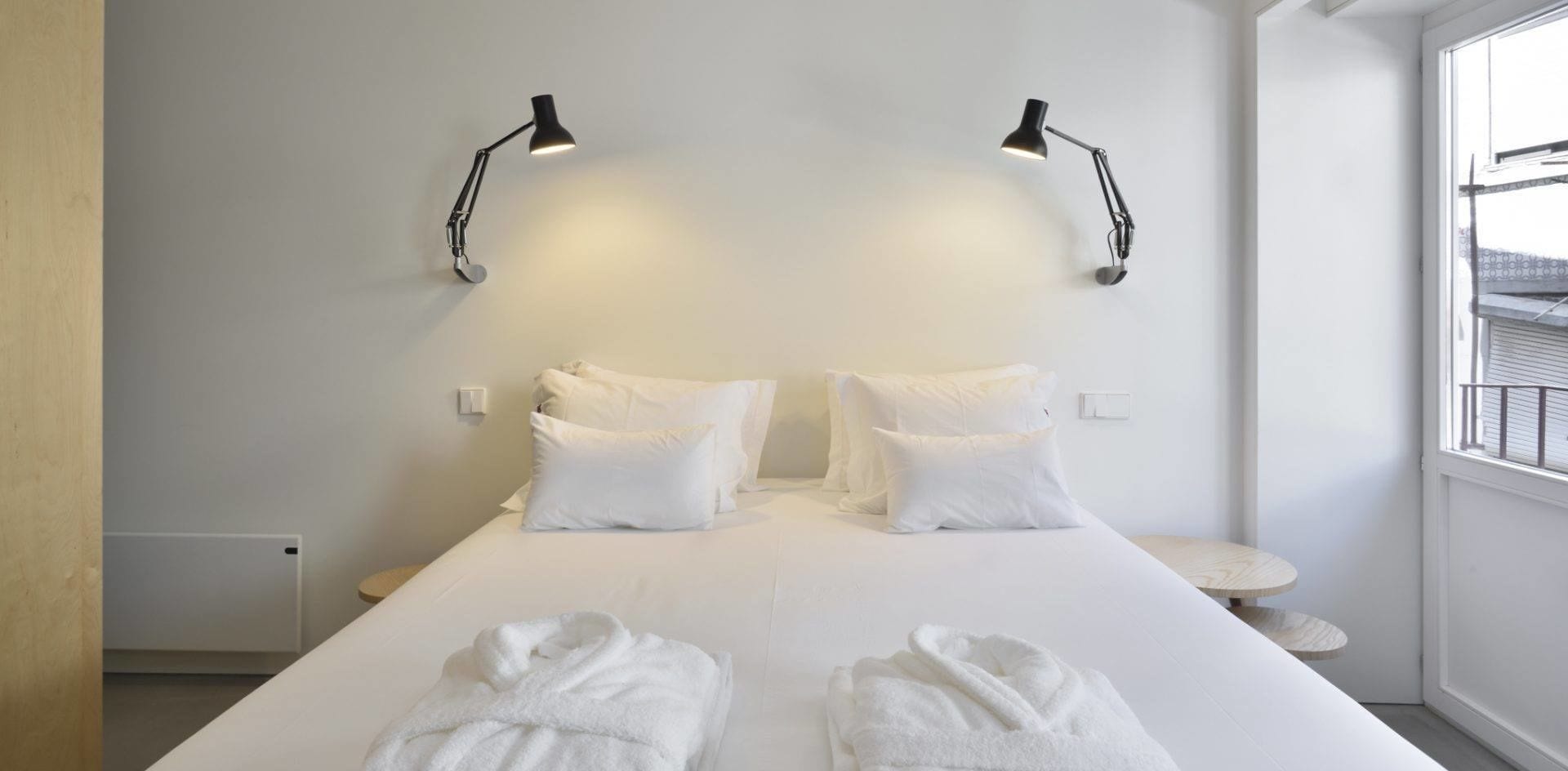 A hotel room with a large bed, two bedside lamps, and a window with a view.