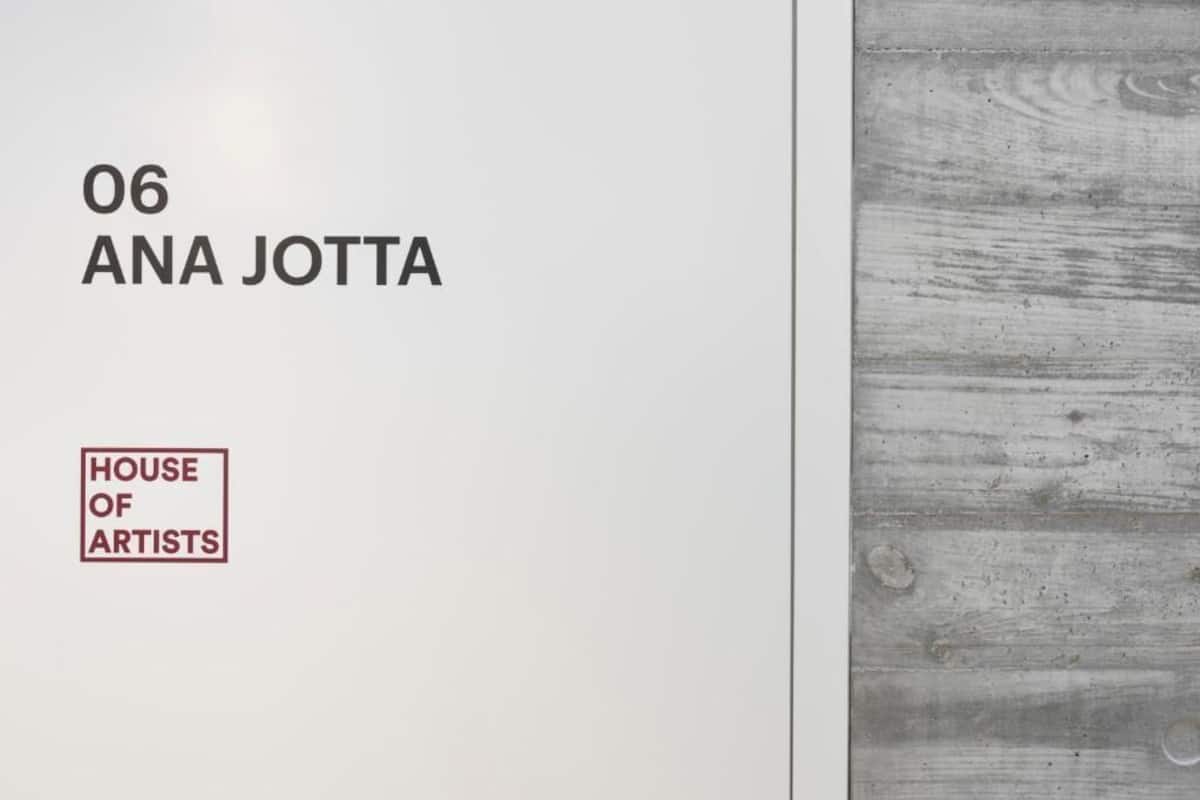 A white wall with the text "06 ANA JOTTA" and a logo for "HOUSE OF ARTISTS".
