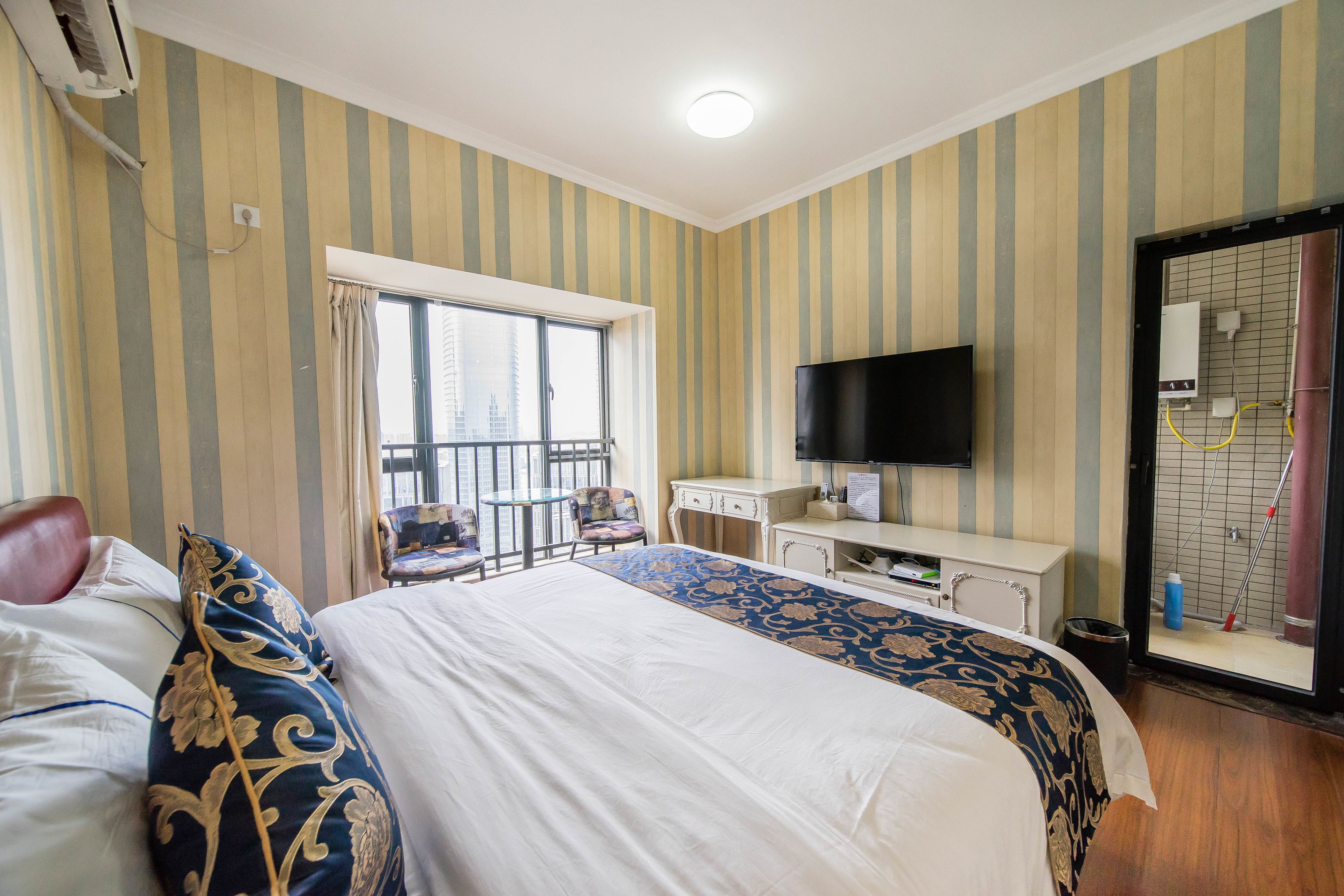 Ein Hotelzimmer mit einem großen Bett, einem Schreibtisch, einem Stuhl, einem Fernseher und einem Fenster mit Vorhängen.