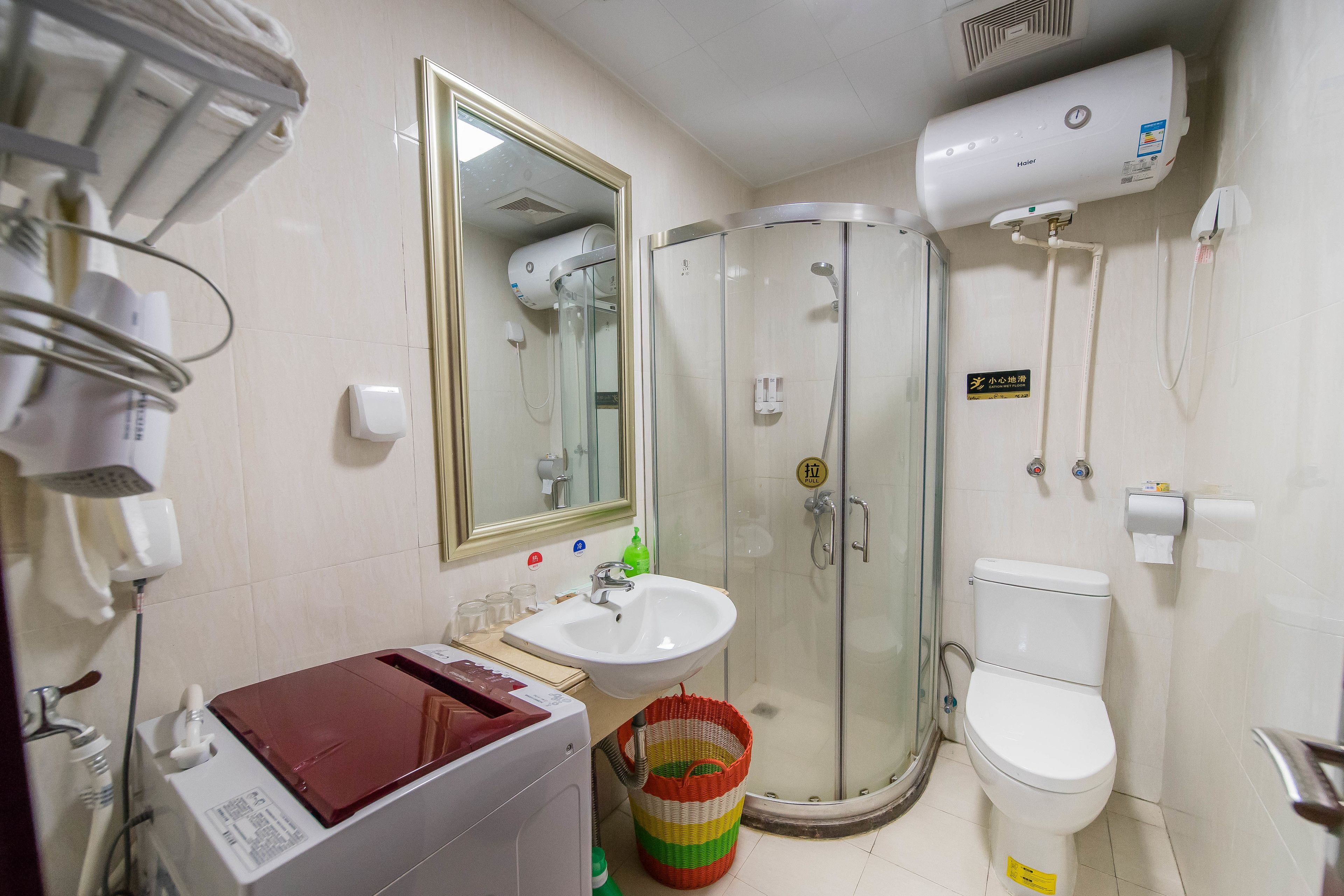 A bathroom with a glass-enclosed shower, a white sink, a toilet, and a mirror.