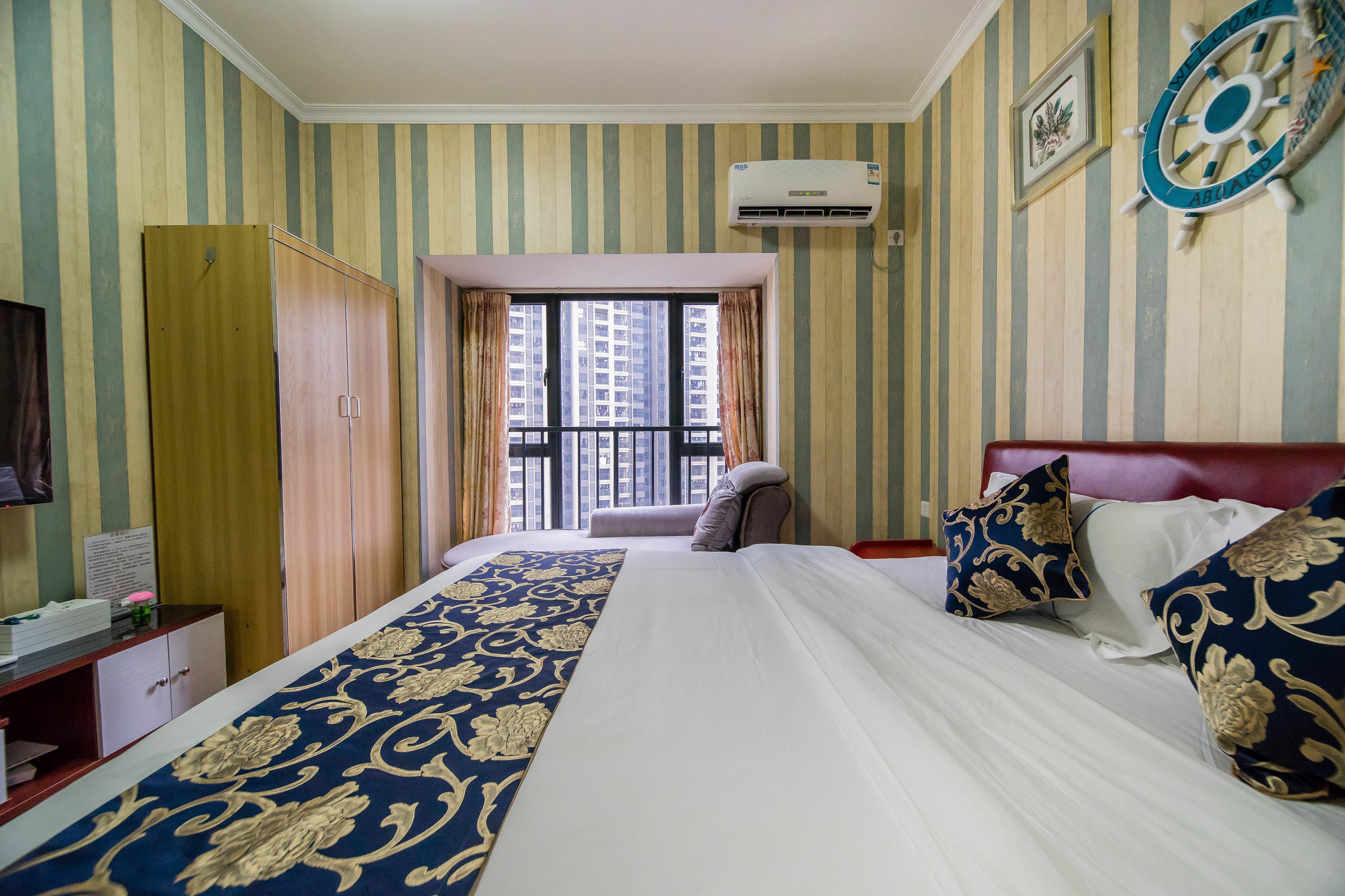 Habitación de hotel con cama, armario, escritorio y ventana con cortinas.