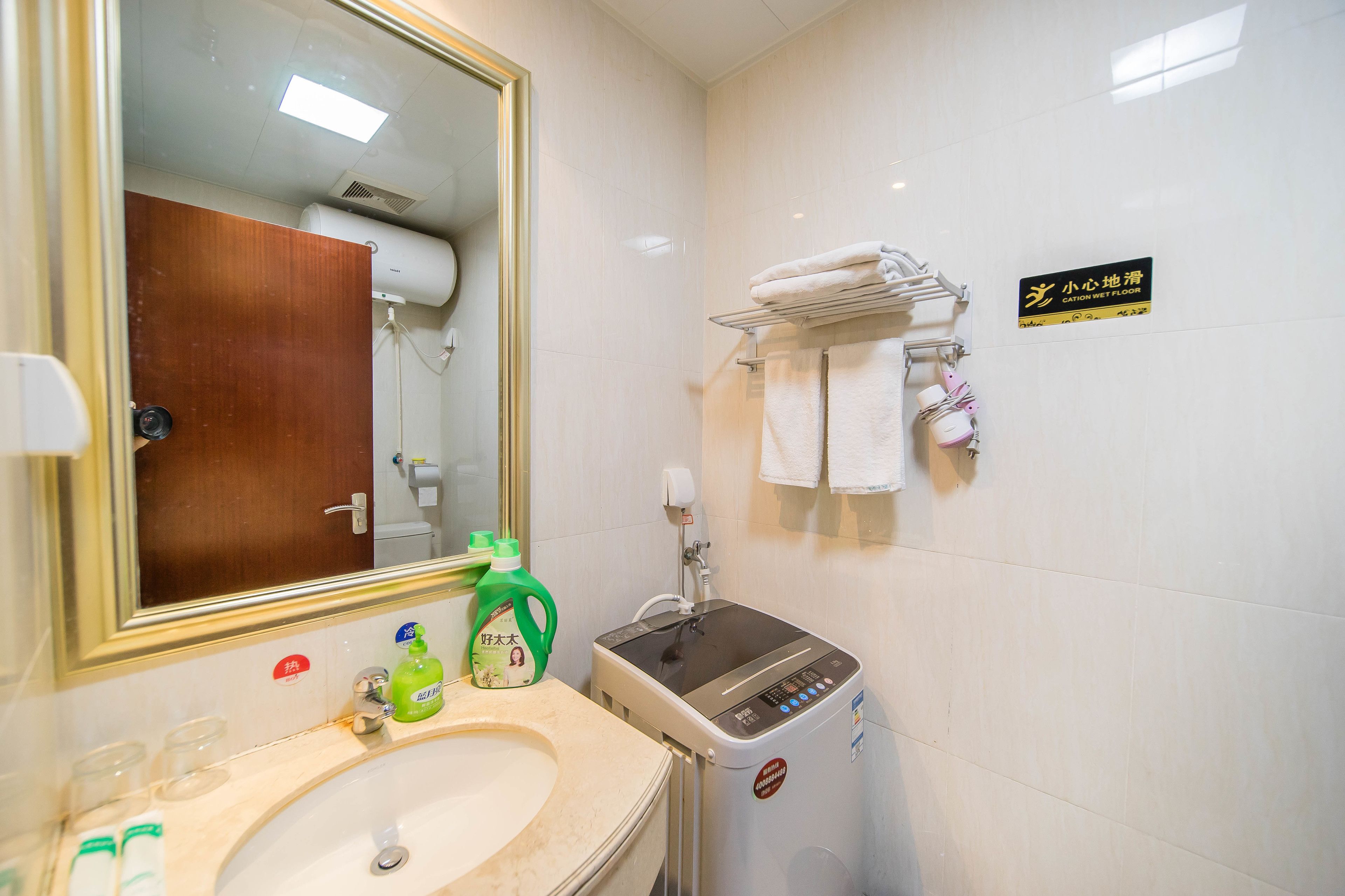 A hotel bathroom with a sink, mirror, towel rack, and a water dispenser.