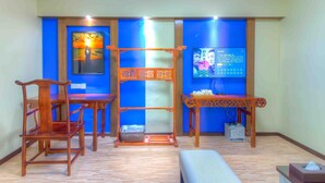 A room with a wooden chair, a small table, a bench, and a wall with a blue panel and a poster. - Pazhou Laiste International ApartHotel Canton Fair Complex Branch (Guangzhou)