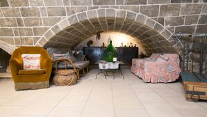 A cozy room with a stone fireplace, a wooden table, and comfortable seating. - Masseria Nanni (Gallipoli)