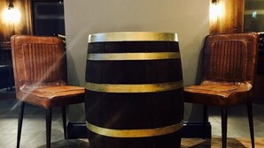 A bar stool with a barrel-shaped base and two leather chairs with vertical slats. - Oxgang Kitchen Bar & Rooms (Grangemouth)
