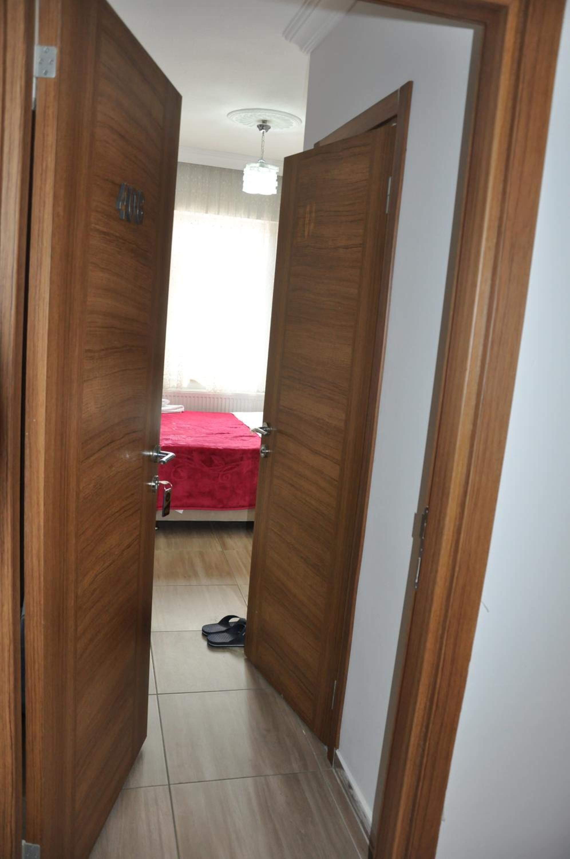 Un pasillo con puertas de madera que dan a un dormitorio con colcha roja.
