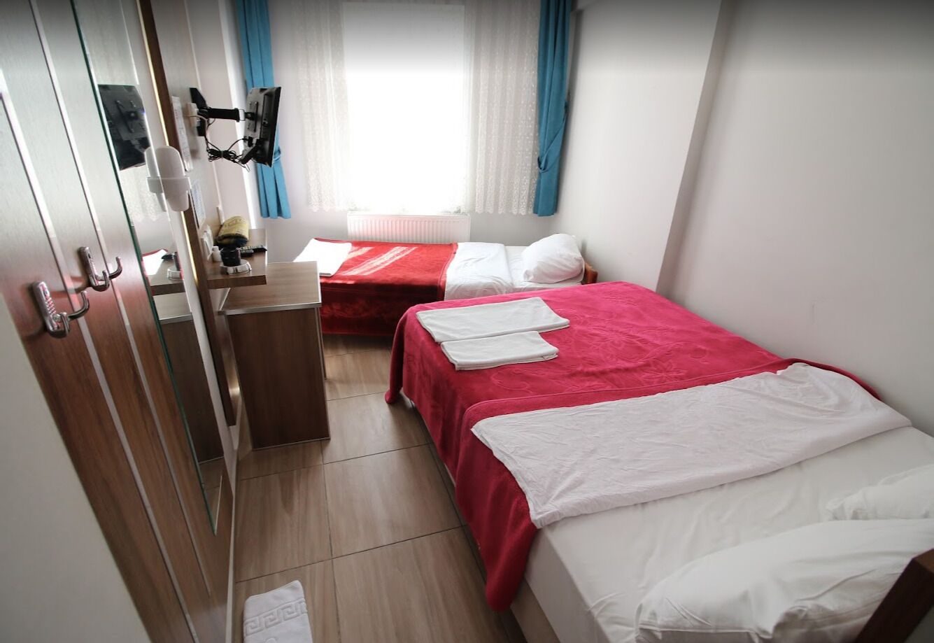 A hotel room with two beds, a desk, and a mirror.