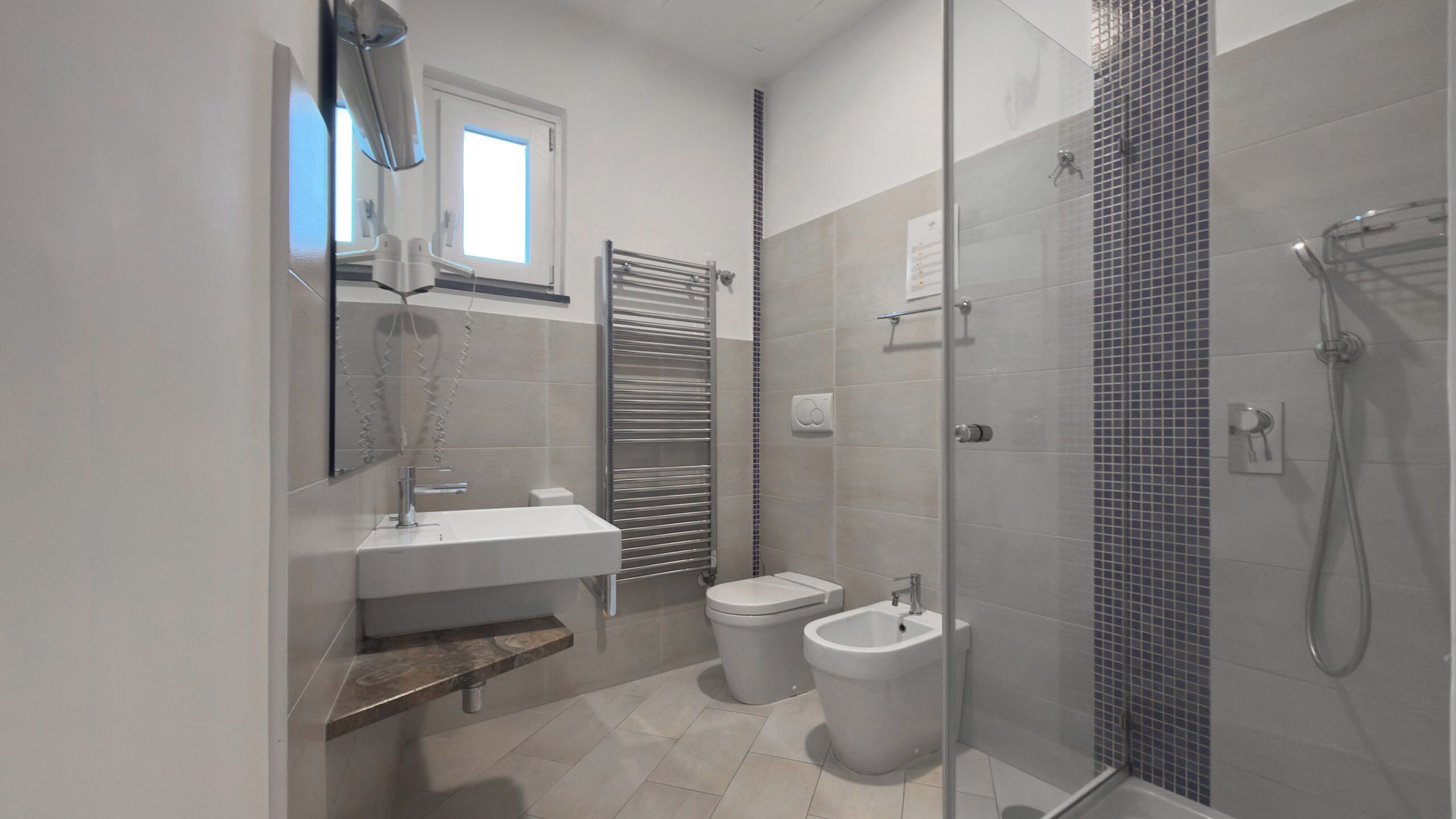 Een moderne badkamer met een douchecabine van glas, een toilet en een bidet.