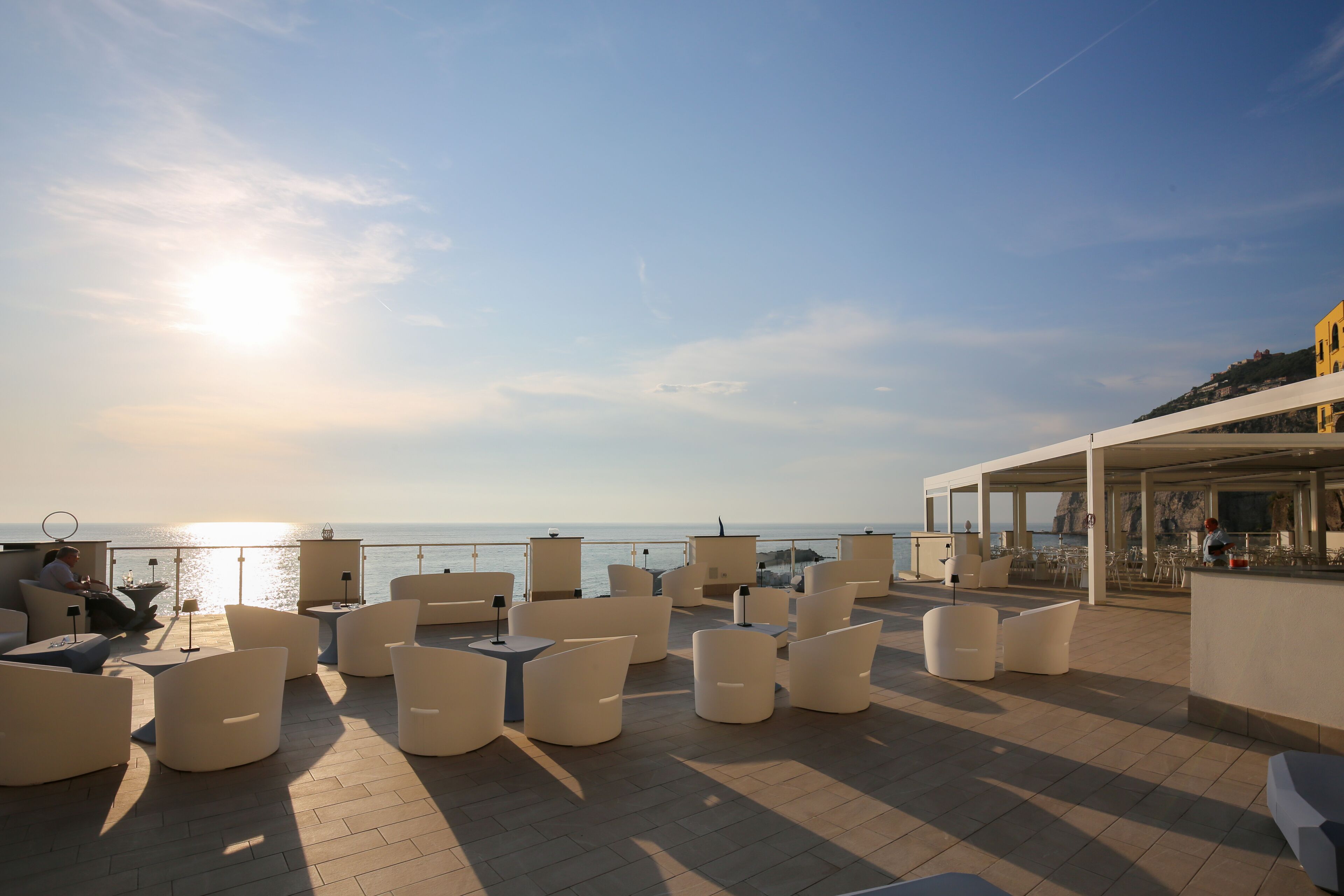 A rooftop terrace with outdoor seating and a view of the sea.
