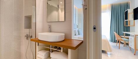 A modern bathroom with a large sink, shower, and a mirror above the sink.