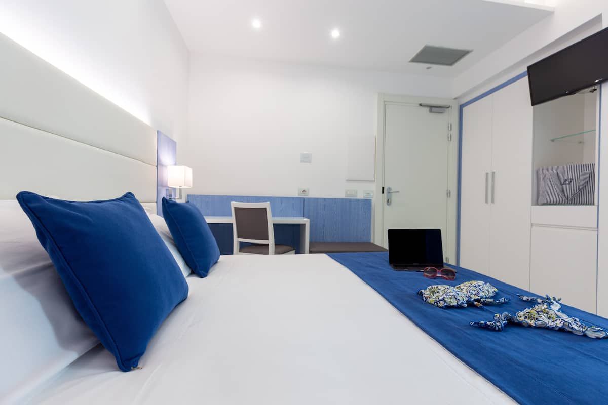 Una habitación de hotel con cama, escritorio, silla, ordenador portátil y armario.