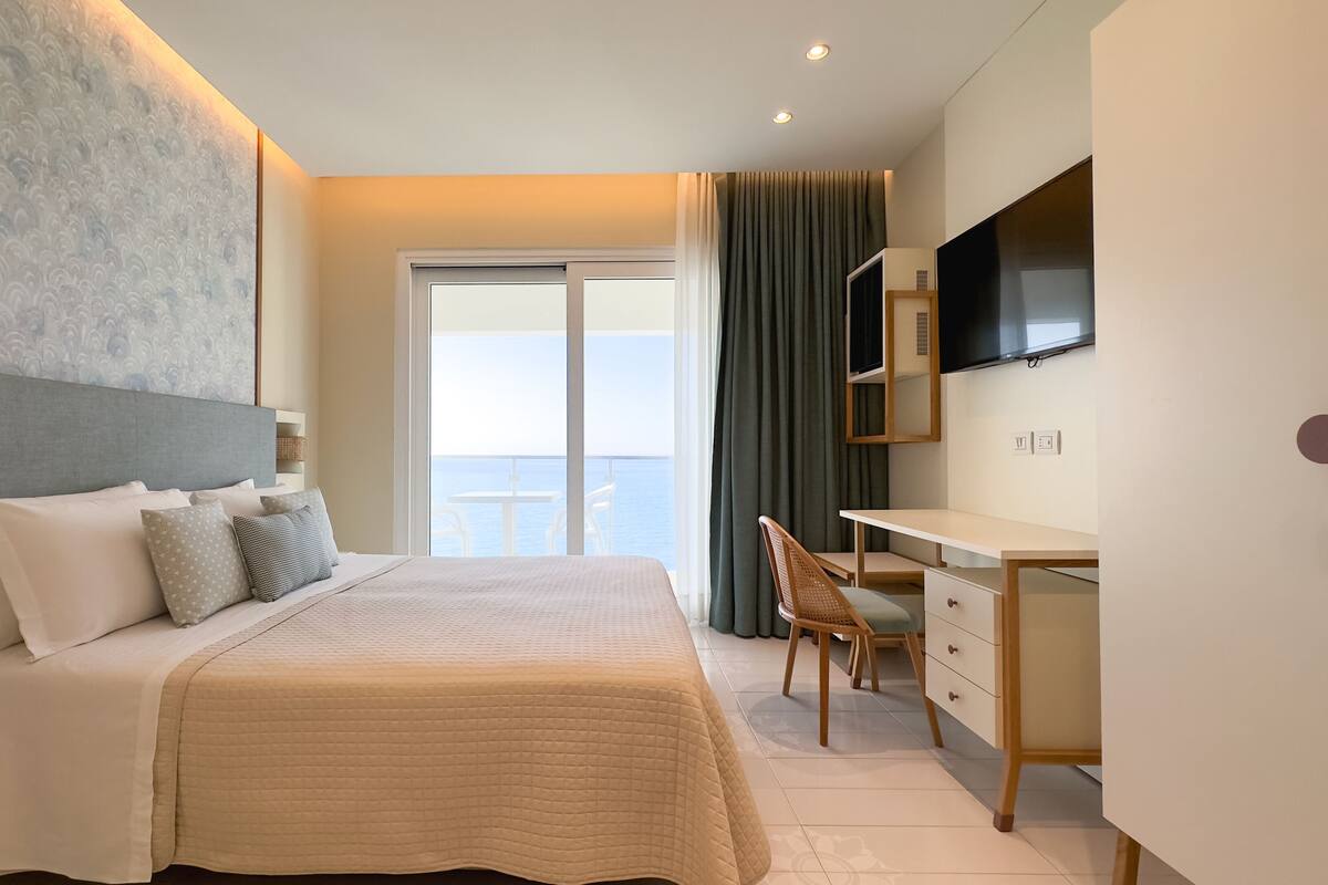 Una habitación de hotel moderna con cama, escritorio, silla y televisor.