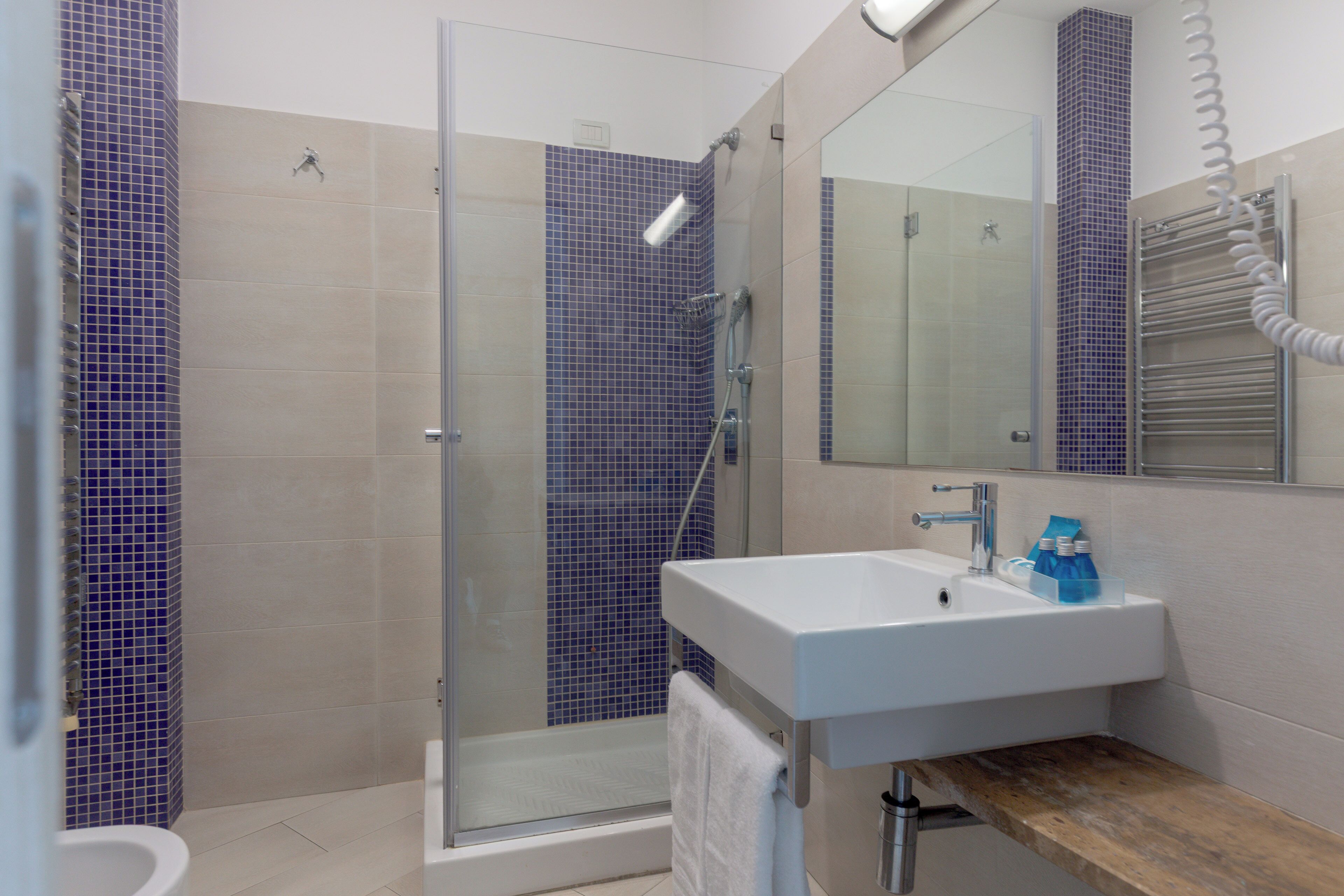 A modern bathroom with a glass shower enclosure, a white sink, and a wooden vanity.