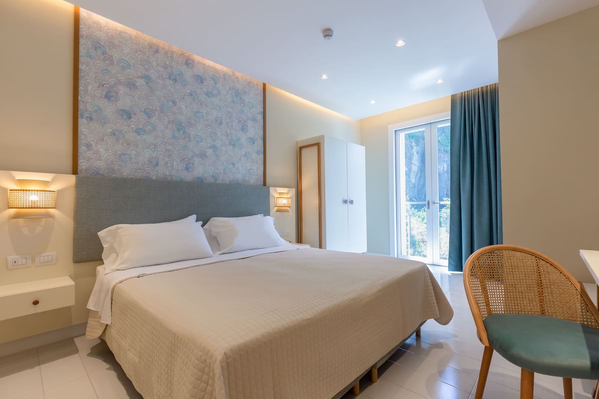 Una habitación de hotel moderna con una cama grande, un escritorio y vistas al exterior.