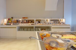 A buffet setup with various food items and beverages, including a fruit bowl, a salad bar, and a selection of meats. - Hotel Giosuè a mare (Meta)