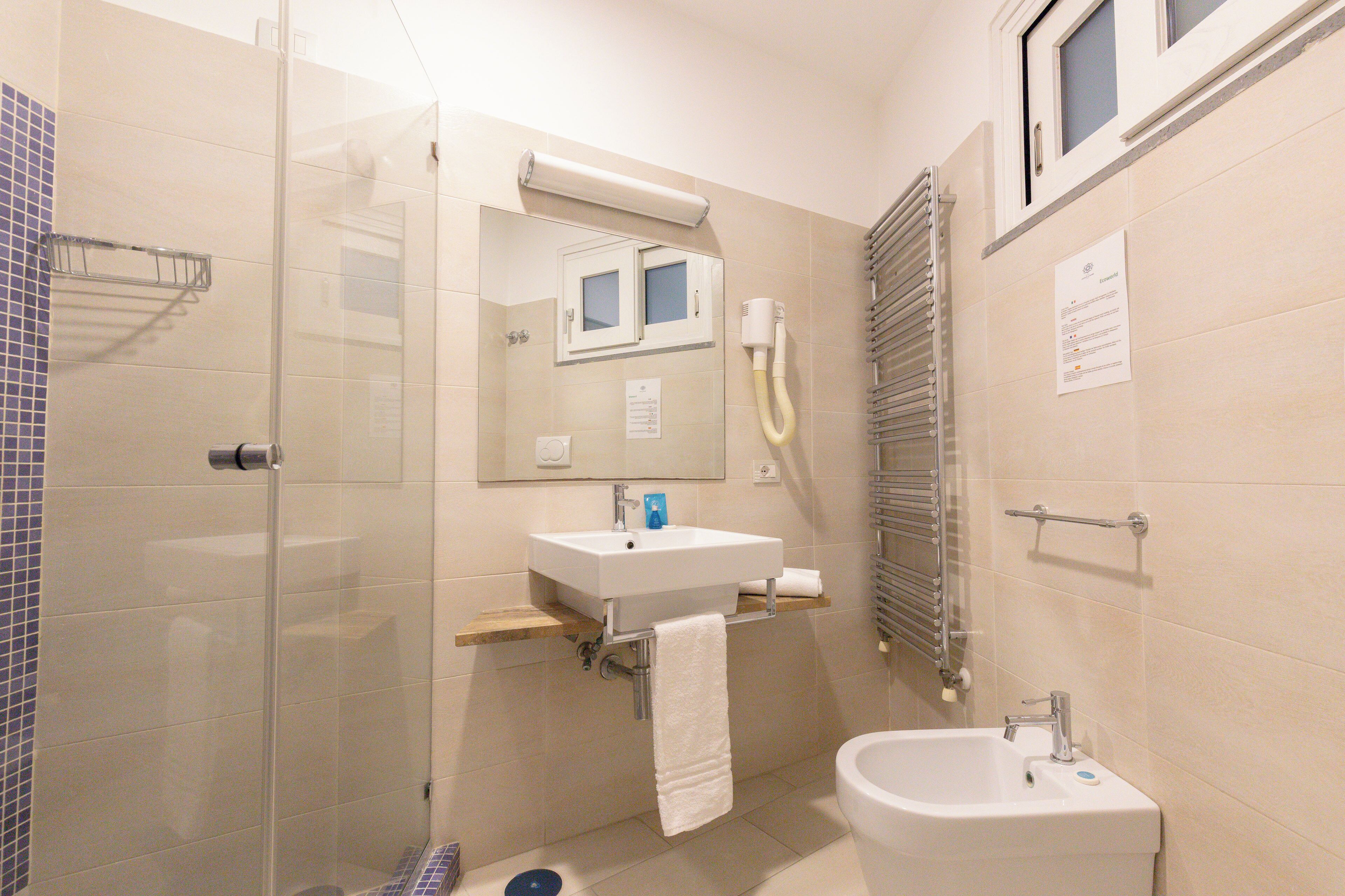 A bathroom with a glass-enclosed shower, a sink with a mirror above it, and a toilet.