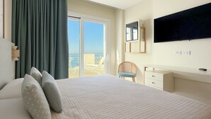 Un dormitorio con cama, una silla, un escritorio, un televisor y vista al mar.