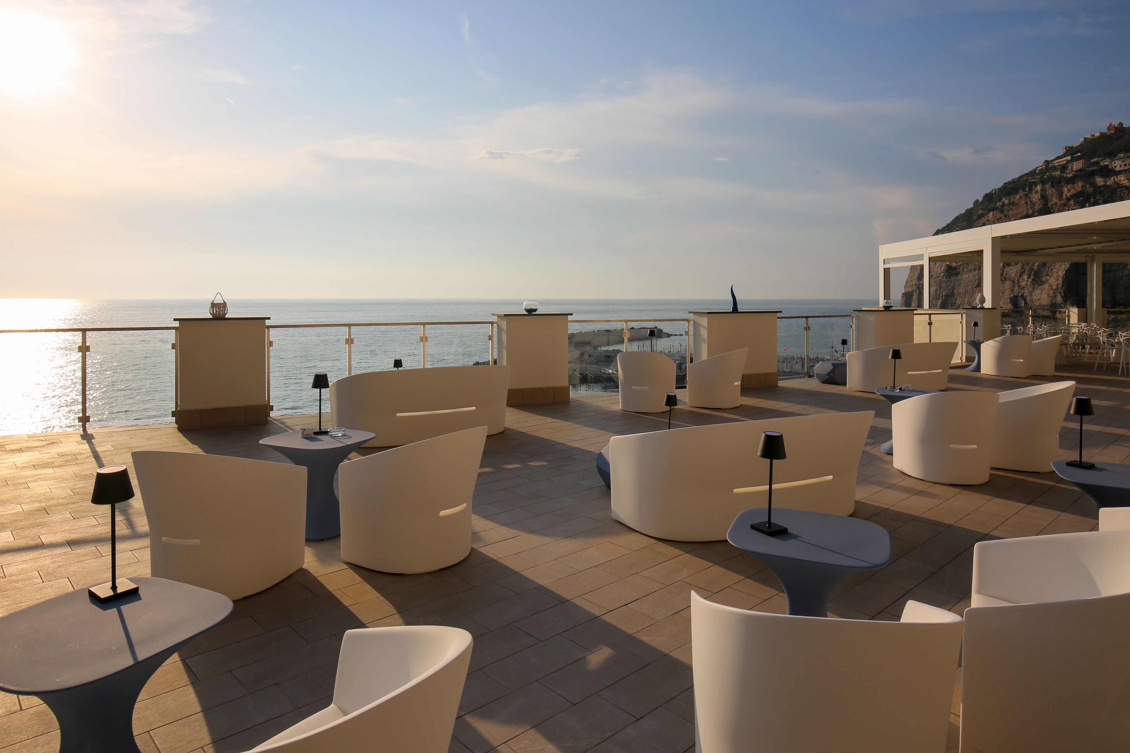 A terrace with white furniture and a view of the sea.