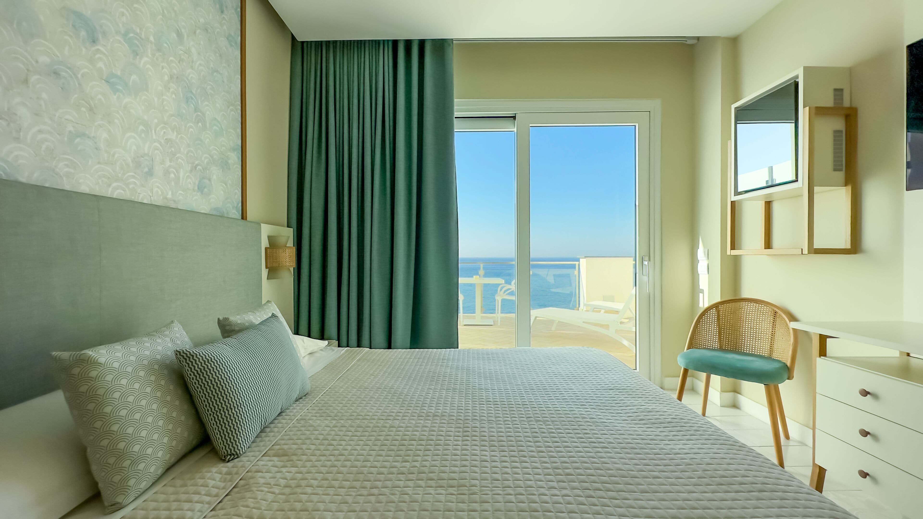Habitación de hotel con cama, una silla, un escritorio y vistas al mar.