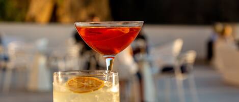A martini glass and a tall glass with a lemon slice on a tray.