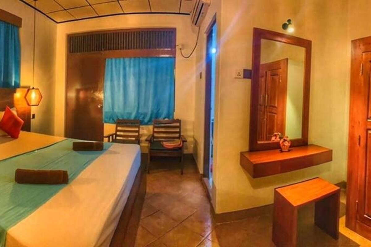 Une chambre d’hôtel comprenant un lit, des tables de chevet, un bureau, une chaise, une armoire et un miroir.