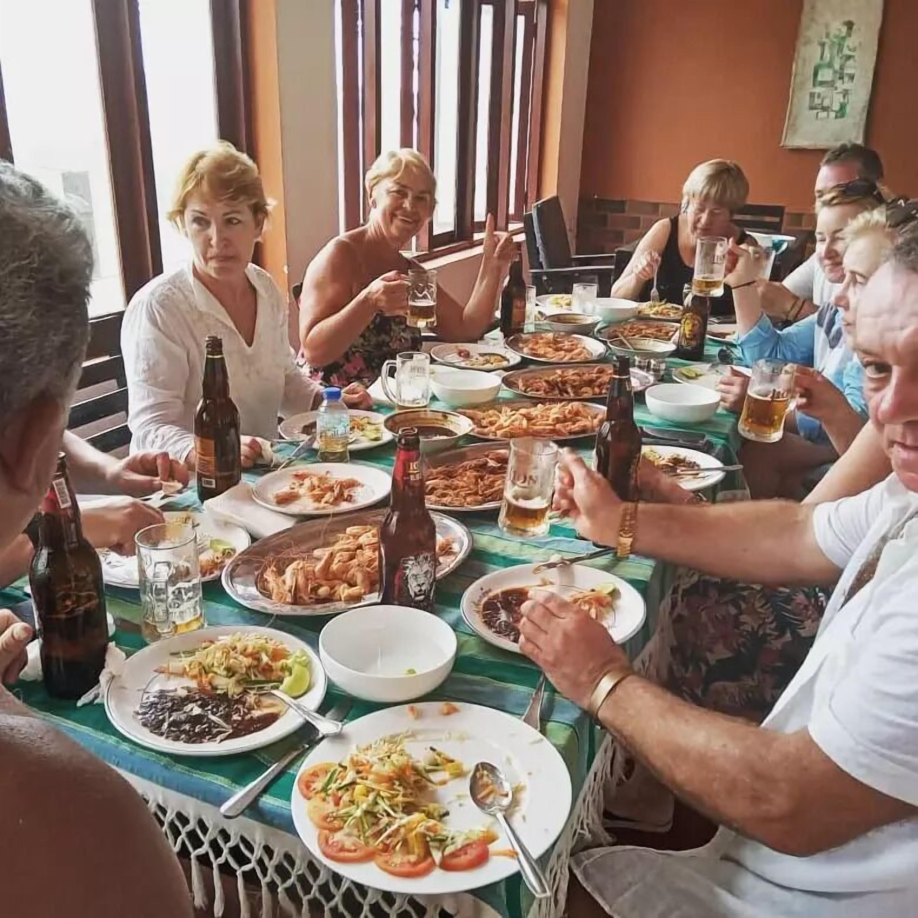 A group of people dining at a table with various dishes and drinks.
