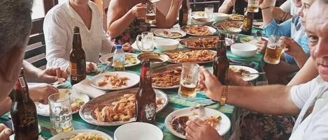 A group of people dining at a table with various dishes and drinks.