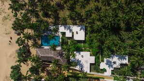 An aerial view of a resort with a pool, palm trees, and a beach. - Mandala Villas (Rekawa)